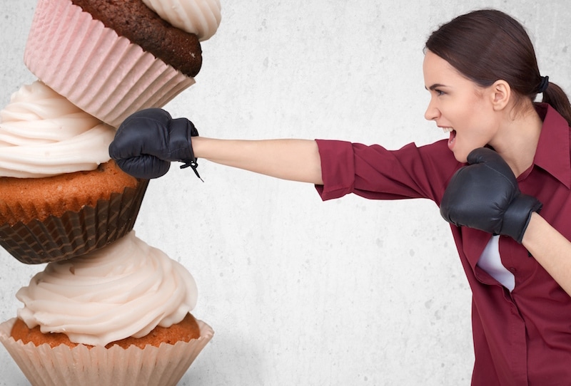 Une femme utilisant des pilules minceur pour perforer une pile de cupcakes.