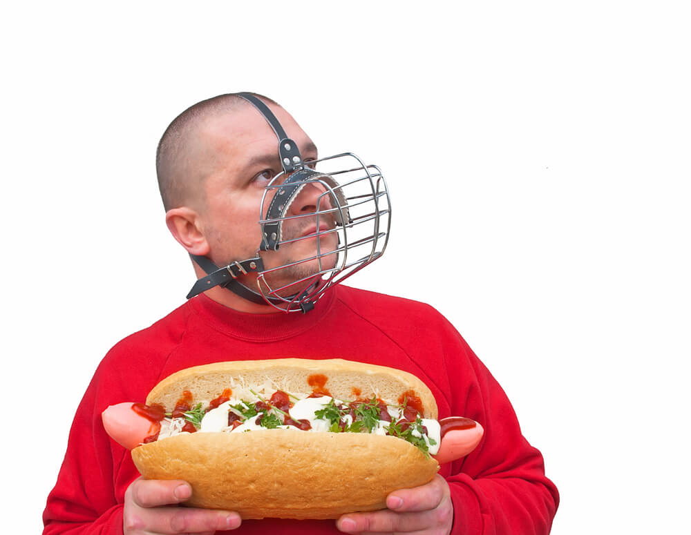 Un homme tenant un hot-dog dans sa bouche.