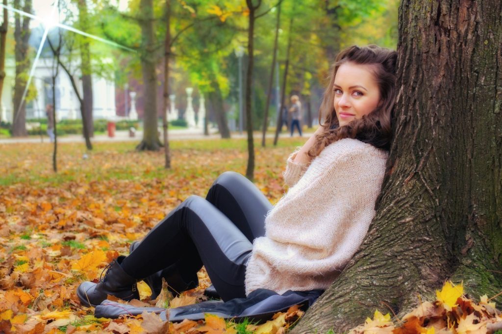 Une jeune femme assise sous un arbre dans le parc, appréciant le voyage de perte de poids Phen375.