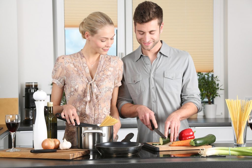 Una giovane coppia segue Weight Watchers mentre prepara il cibo in cucina.