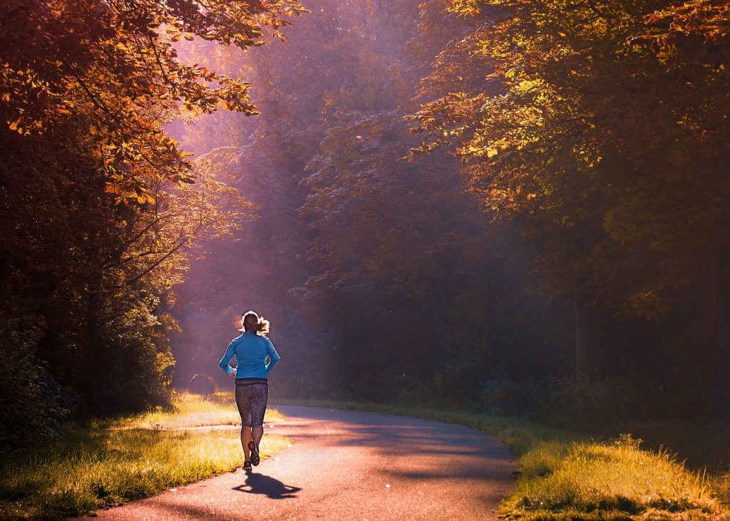 Una donna sta facendo jogging lungo un sentiero nel bosco.