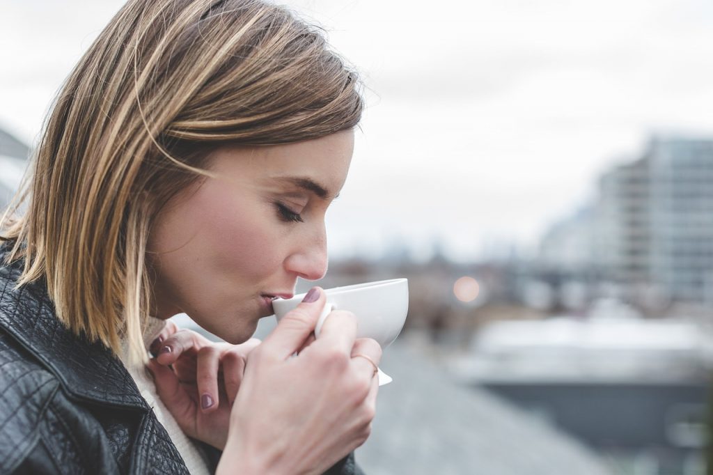 Una donna che si gode una tazza di caffè infuso con orthosiphon su un tranquillo tetto.
