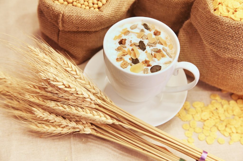 Una tazza di caffè con una ciotola di cereali e sacchi di grano, perfetta per un regime salutare.
