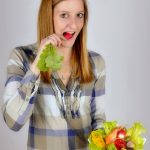 Una donna tiene in mano una ciotola di insalata.