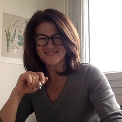 Una donna con gli occhiali seduta a una scrivania.
