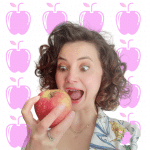 Una donna che tiene una mela davanti a uno sfondo rosa.