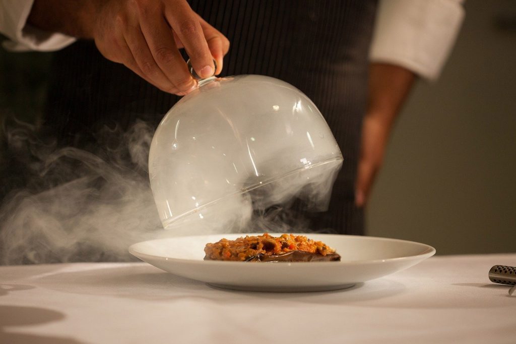 Uno chef sta mettendo il cibo su un piatto con un coperchio sopra.
