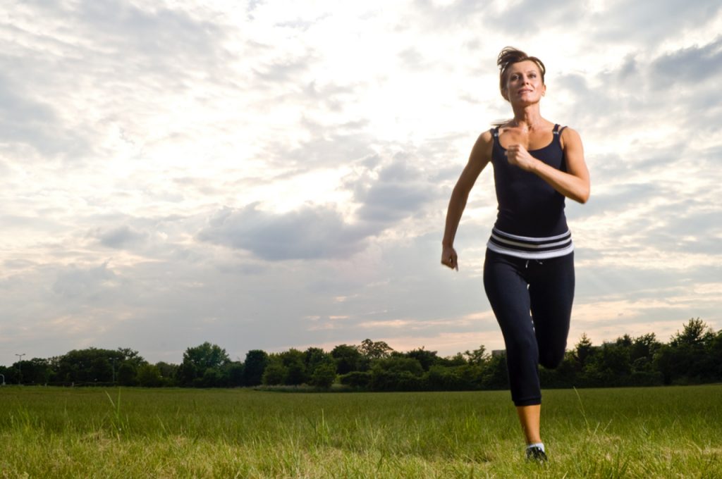 Una donna che fa jogging in un campo con un cielo nuvoloso.
