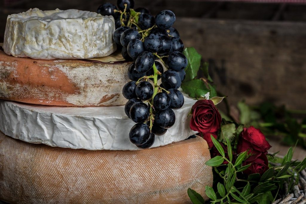 Una pila di formaggio con uva e rose.