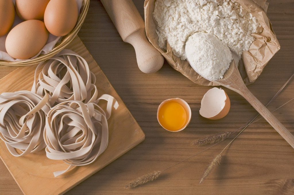 Ingredienti per fare la pasta su un tavolo di legno.