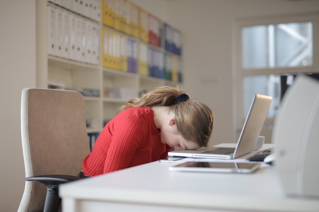 donna stanca che appoggia la testa contro il suo computer per dimostrare la sua stanchezza emotiva o invernale